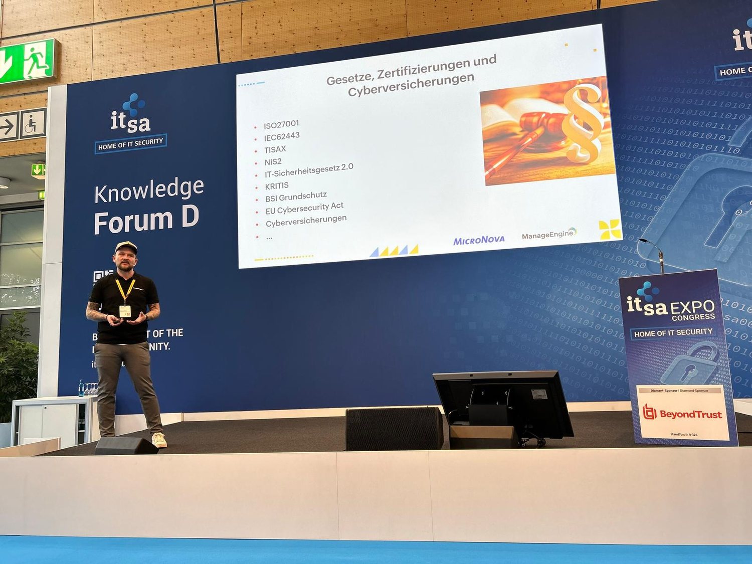 Andreas Klare im Knowledge Forum D auf der it-sa, im Hintergrund eine Folie zu Gesetzen, Zertifizierungen und Cyberversicherungen.